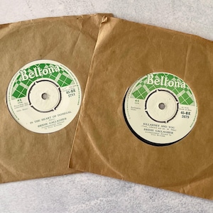 Pode incluir: Dois discos de vinil de 45 RPM de Bridie Gallagher em capas de papel castanho. Os rótulos Beltona são brancos com padrões axadrezados verdes. Um disco intitula-se In the Heart of Donegal e o outro Killarney and You, ambos série 45-BE.