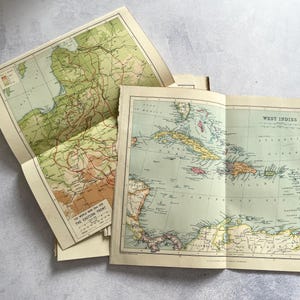 Puede incluir: Dos mapas de papel antiguos en tonos verde, beige y negro. Un mapa muestra las Indias Occidentales con el mar Caribe, mientras que el otro representa el Frente Oriental durante la Primera Guerra Mundial, incluyendo una leyenda y escala.