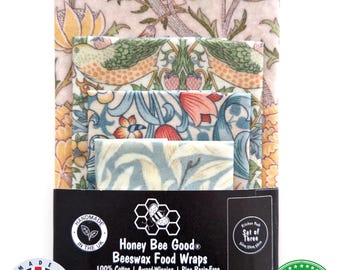 Może przedstawiać: Trzy woskowijki z motywami kwiatów i ptaków w odcieniach różu, zieleni i błękitu. Opakowanie zawiera tekst Honey Bee Good Beeswax Food Wraps, 100% Cotton, Award-Winning, Pine Resin-Free oraz Certified Food Safe.