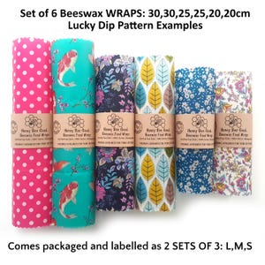 May include: A set of six beeswax food wraps in various patterns, including pink polka dots, koi fish, floral, and leaf prints. Each wrap is secured with a paper band labeled Honey Bee Good. Sizes include 30, 25, and 20 cm dimensions.
