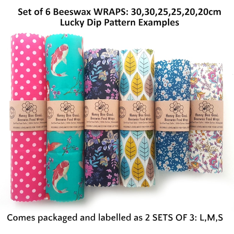 May include: A set of six beeswax food wraps in various patterns, including pink polka dots, koi fish, floral, and leaf prints. Each wrap is secured with a paper band labeled Honey Bee Good. Sizes include 30, 25, and 20 cm dimensions.