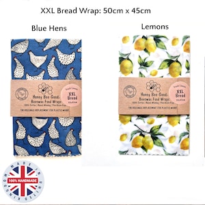May include: Two XXL beeswax food wraps measuring 50cm x 45cm. One wrap features a blue background with white hen patterns, while the other has a white background with yellow lemon and green leaf patterns. Both have paper bands labeled Honey Bee Good.