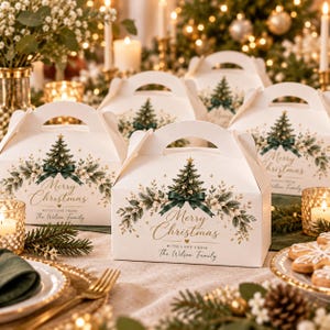 May include: White cardboard gable boxes featuring a printed Christmas tree, green ribbon, and foliage design. The text reads Merry Christmas with love from The Wilson Family. These boxes are arranged on a table with holiday decor.