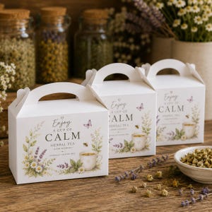 May include: Three white cardboard gable boxes for herbal tea, each featuring a printed illustration of a teacup, lavender, chamomile flowers, a butterfly, and a bee. The text on the boxes reads Enjoy A CUP OF CALM HERBAL TEA HAND BLENDED.