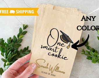 May include: A stack of brown paper bags with a graduation cap design and the text "One smart cookie" and "Sarah Williams, Class of 2024".