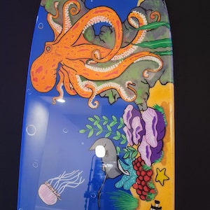 May include: A white ceramic mug with a black handle and the text "But First, Coffee" in a bold, black font. The mug is set against a blurred background, suggesting a cozy setting.