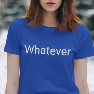 May include: A royal blue t-shirt with the word "Whatever" printed in white. The shirt has short sleeves and a crew neck. The image is a medium shot, focusing on the shirt and the upper body.
