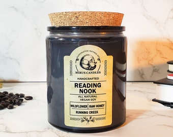 Może przedstawiać: Szklany słoik na świecę w kolorze czarnym z korkową pokrywką i etykietą z napisem "Handcrafted Natural Soy", "Mirus Candles", "Handcrafted", "Reading Nook", "All Natural Vegan Soy", "Wildflower Raw Honey" i "Running Creek".