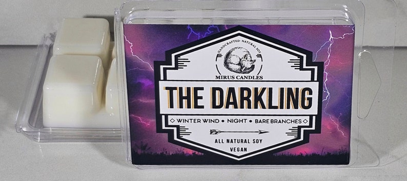 Puede incluir: Un contenedor de pl&aacute;stico transparente con tres cubos de cera blanca. El contenedor tiene una etiqueta con un fondo morado y negro y un gr&aacute;fico de rayos. La etiqueta dice "HANDCRAFTED NATURAL SOY MIRUS CANDLES THE DARKLING WINTER WIND NIGHT BARE BRANCHES ALL NATURAL SOY VEGAN".
