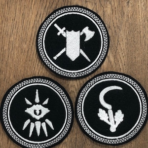 May include: Three black and white embroidered patches with a white border. The patches feature a sword and axe crossed over a shield, a stylised eye with rays, and a sickle with leaves.