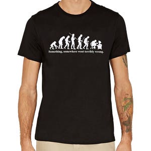 Könnte beinhalten: Schwarzes T-Shirt mit einer weißen Grafik der Evolution des Menschen, die mit einer Person endet, die an einem Computer sitzt. Der Text unter der Grafik lautet "Something, somewhere went terribly wrong."