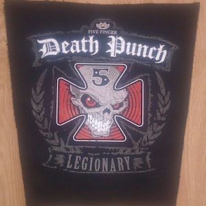 May include: Black and white embroidered patch with the text "Five Finger Death Punch" and a skull with a cross behind it. The skull has red eyes and the cross has red stripes. The text "Legionary" is below the skull.