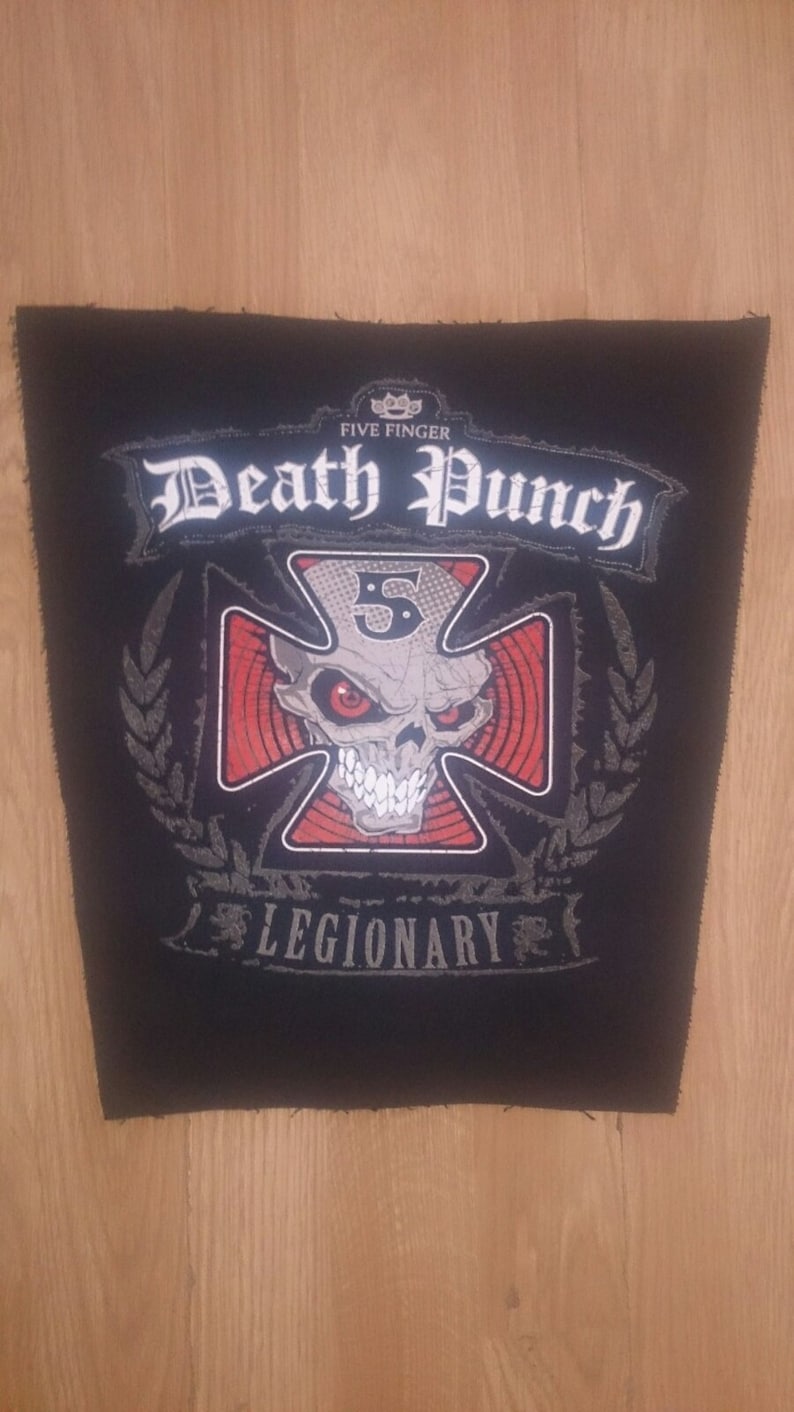 May include: Black and white embroidered patch with the text "Five Finger Death Punch" and a skull with a cross behind it. The skull has red eyes and the cross has red stripes. The text "Legionary" is below the skull.