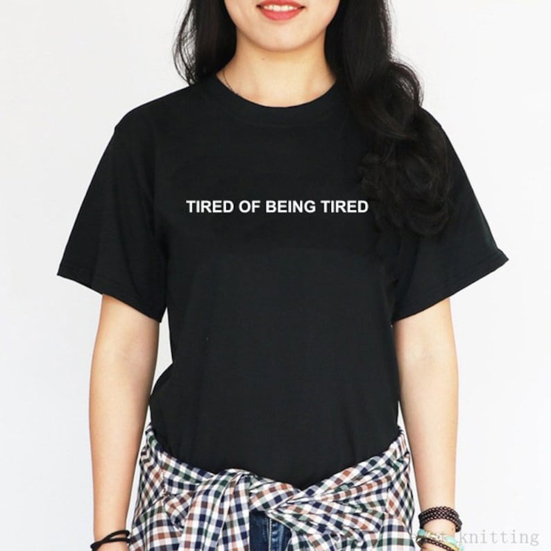 May include: Black t-shirt with white text that reads "TIRED OF BEING TIRED".