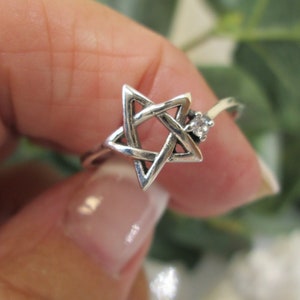 May include: A silver ring with a star of David design and a small clear stone accent.