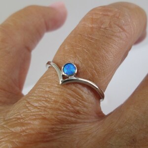 May include: A silver ring with a blue opal gemstone set in a V-shaped band.