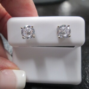 May include: A pair of silver stud earrings with clear round cubic zirconia stones.