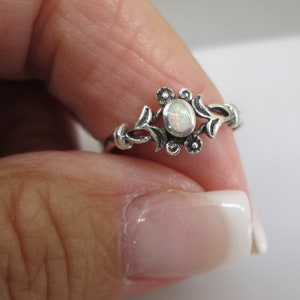 May include: A silver ring with a white opal stone set in a floral design.