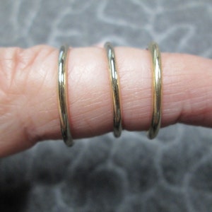 May include: Three gold-colored metal rings stacked on a finger.