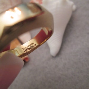 May include: A gold band ring with the inscription "Tiffany & Co. Italy" on the inside of the band.