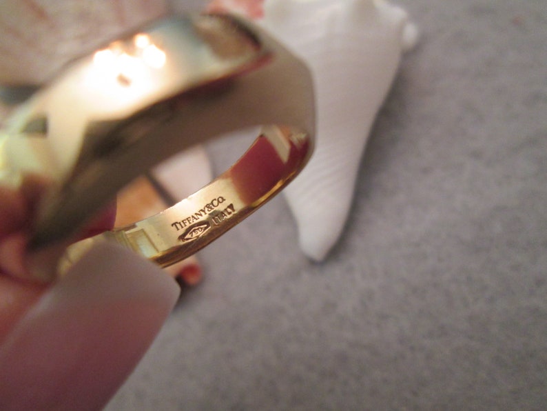 May include: A gold band ring with the inscription "Tiffany & Co. Italy" on the inside of the band.