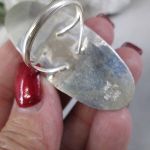 May include: A silver ring with an oval shaped stone. The ring is marked "DINE BELYTE 925".