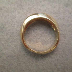 May include: A gold band ring with a smooth, rounded surface.