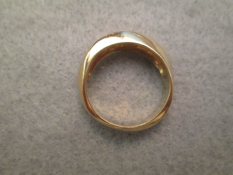 May include: A gold band ring with a smooth, rounded surface.