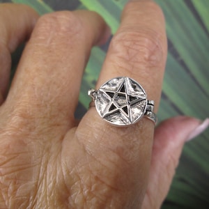 May include: A silver ring with a pentagram design. The ring is adjustable and has a smooth finish.