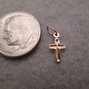 May include: A small gold cross pendant charm. The cross is about the size of a dime.