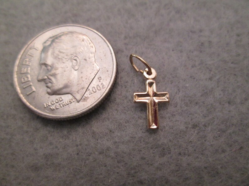 May include: A small gold cross pendant charm. The cross is about the size of a dime.