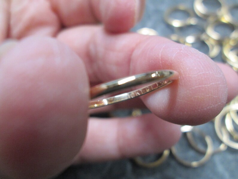 May include: A close-up of a gold-colored metal key ring with the inscription "MADE IN USA" on the inside of the ring.