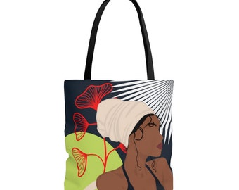 May include: A tote bag with a colorful illustration of a woman with a white head wrap and red flowers. The background is black with white and black stripes.