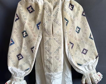 May include: A white embroidered blouse with a high neckline and long sleeves. The sleeves and front of the blouse feature intricate geometric patterns in shades of blue, green, red, and purple.