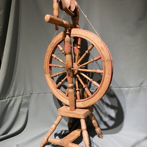 Roda de fiar manual antiga em funcionamento, ferramenta de fiar vintage do início do século XX, roca artesanal, funcional e decorativa.