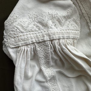 Op de afbeelding: Wit linnen blouse met delicate witte borduurwerk rond de halslijn en mouwen.