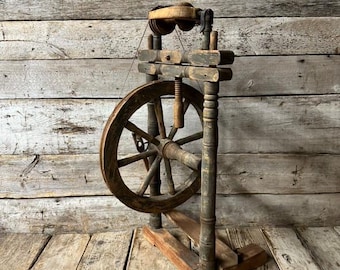 Könnte beinhalten: Antikes Holzspinnrad mit einem großen Holzrad und einem kleineren Holzrad oben. Das Spinnrad ist in Braun- und Schwarztönen bemalt.