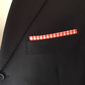 May include: A navy blue blazer with a red and white checkered pocket square.