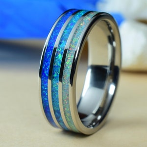 May include: A silver tungsten carbide ring with three blue and white opal inlay bands.