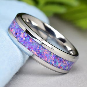 Puede incluir: Un anillo de plata con una incrustación de ópalo morado y rosa.