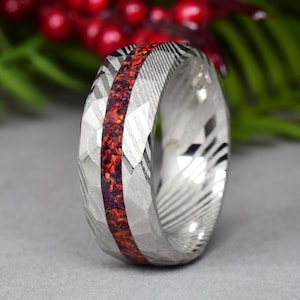 Può includere: Un anello d'argento con un'intarsio rosso e nero. L'anello ha una finitura martellata e un motivo testurizzato.