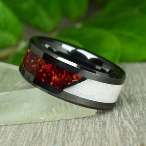 Peut inclure: Une bague en céramique noire avec un incrustation rouge et blanche. La bague a une finition polie et un bord biseauté.