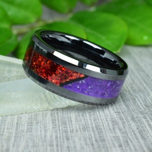 May include: A black ceramic ring with a red and purple inlay. The ring has a beveled edge and a polished finish.