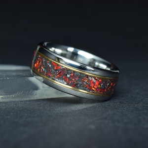 Può includere: Un anello in acciaio inossidabile con una fascia di intarsi in opale rosso e nero e un accento dorato.