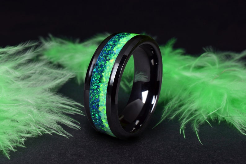 May include: A black tungsten carbide ring with a green and blue opal inlay.
