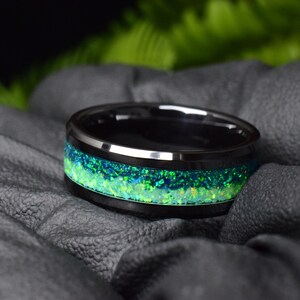 May include: A black tungsten carbide ring with a green and blue opal inlay.