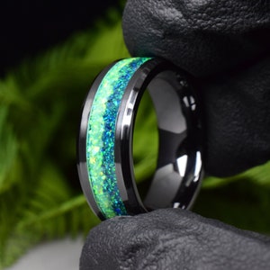 May include: A black tungsten carbide ring with a green and blue opal inlay.
