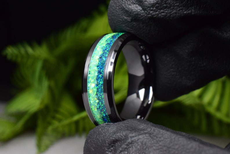 May include: A black tungsten carbide ring with a green and blue opal inlay.