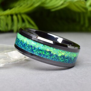 May include: Black ceramic ring with a green and blue opal inlay.