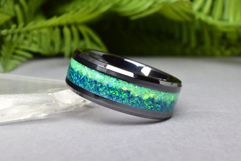 May include: Black ceramic ring with a green and blue opal inlay.